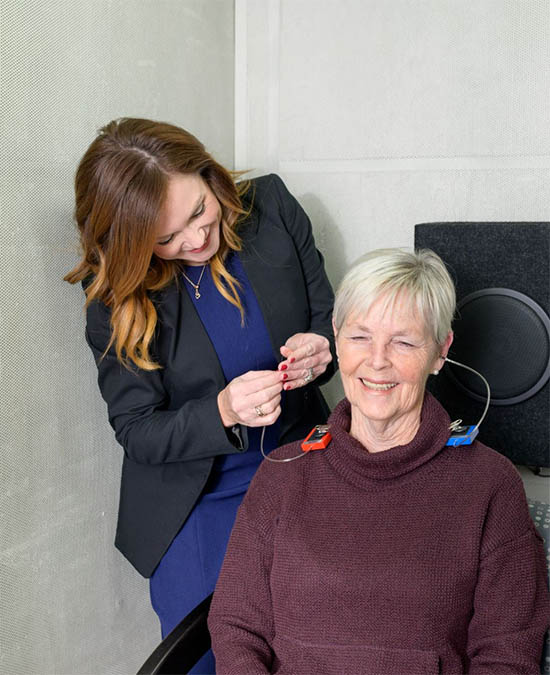 Dr. Erica helping a patient with hearing aids adjustment