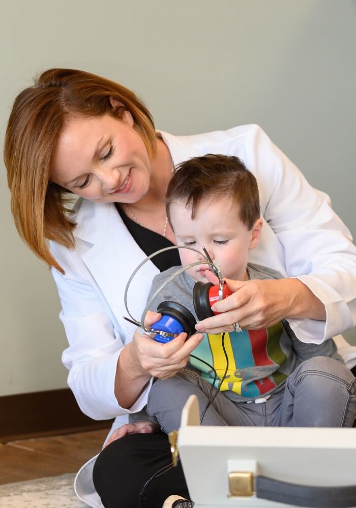 Dr. Erica Person, Au.D, CCC-A performing hearing test on a child